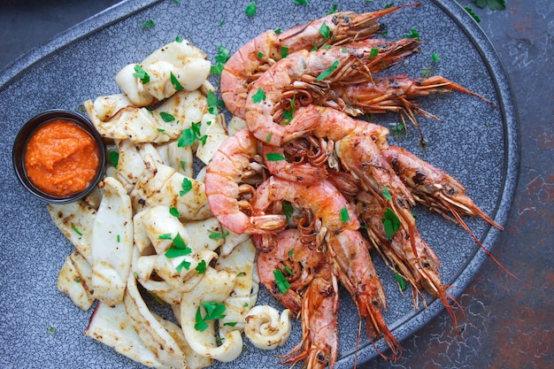 Plato con mariscos, langostinos y calamares, Menú de pescado en el restaurante, Fondo oscuro