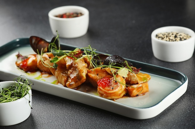 Plato de mariscos con mejillones y camarones toped microgreen closeup.