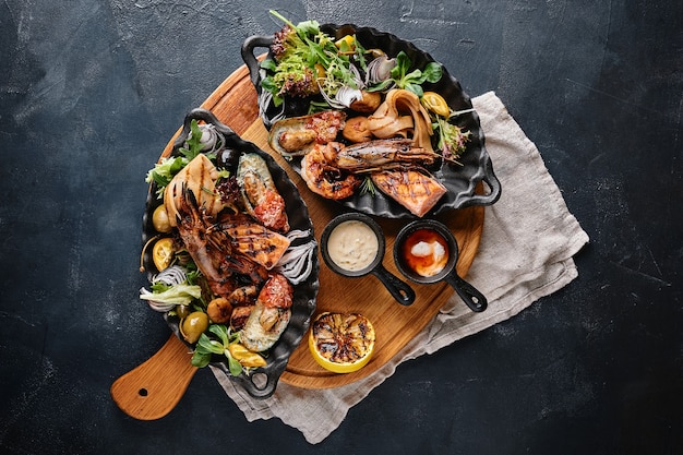 Plato de mariscos a la plancha. Surtido de deliciosos mariscos a la plancha con verduras. Bastardos mixtos a la plancha con salsa de pimientos y verduras. Fondo azul.