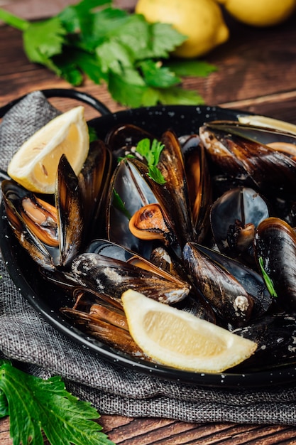 Plato de mejillones al vapor con limón y perejil sobre una mesa de madera rústica.