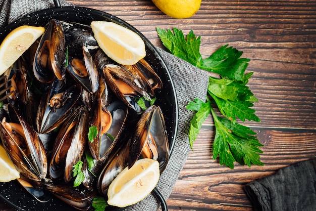 Plato de mejillones al vapor con limón y perejil sobre una mesa de madera rústica.