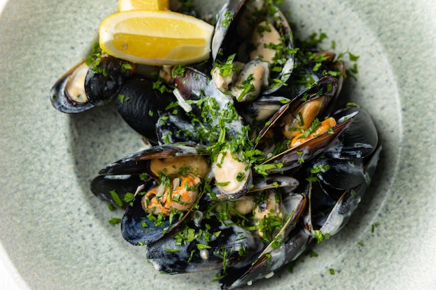 Un plato de mejillones con una rodaja de limón al lado