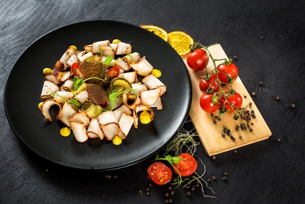 plato de muchos trozos de manteca de cerdo con verduras sobre fondo negro