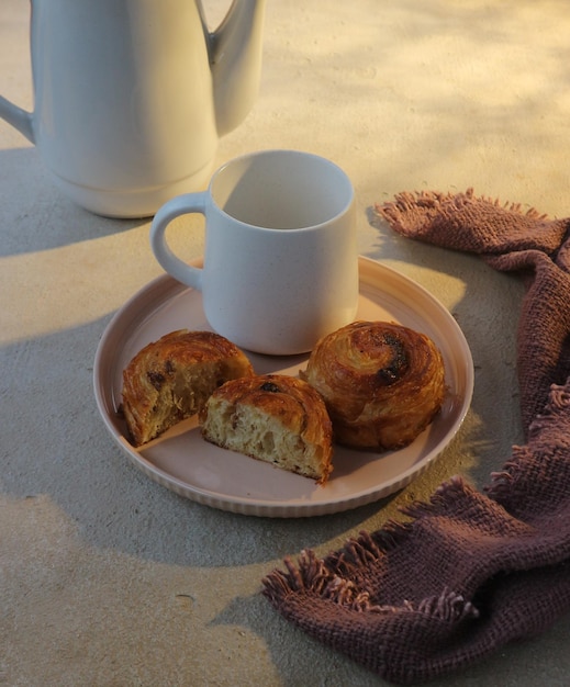 Un plato de muffins y una taza de café sobre una mesa.