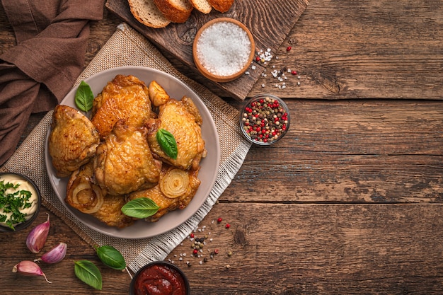 Un plato con muslos de pollo frito, albahaca fresca, ajo y salsas