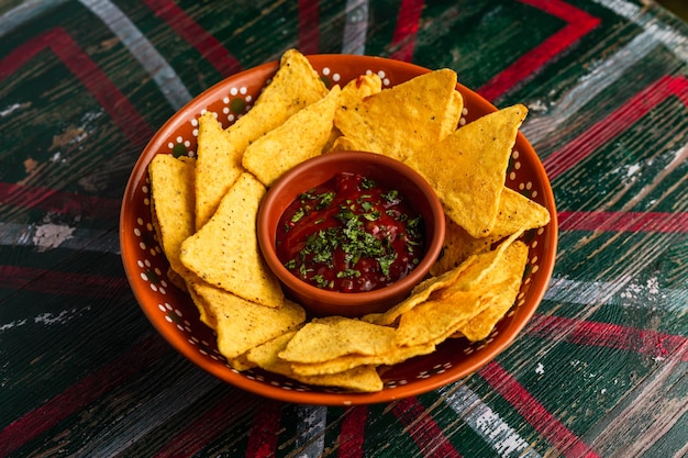 Un plato de nachos con salsa picante en una mesa de madera