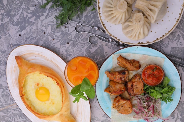 el plato nacional georgiano khachapuri y khinkali sobre la mesa en platos y kebab de cordero