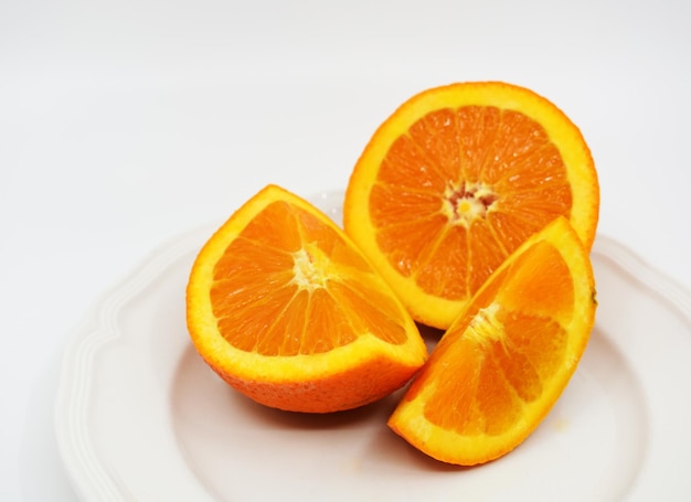 Un plato con naranjas y una de ellas tiene un corte por la mitad.