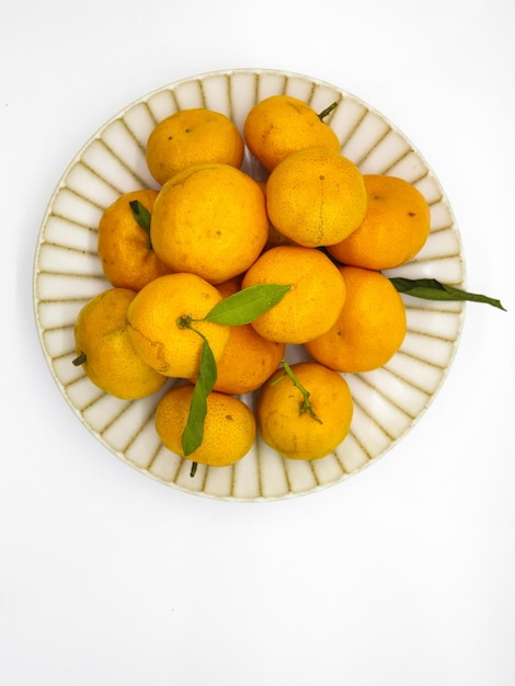 Un plato de naranjas con hojas verdes