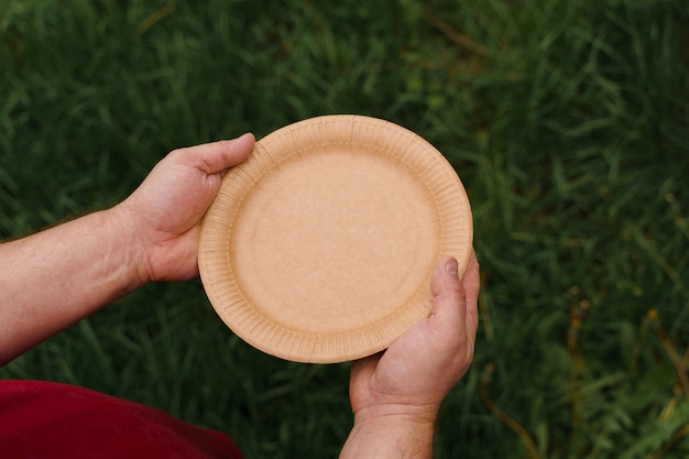 Foto plato natural ecológico. conjunto de utensilios ecológicos desechables en manos sostenibilidad del planeta.