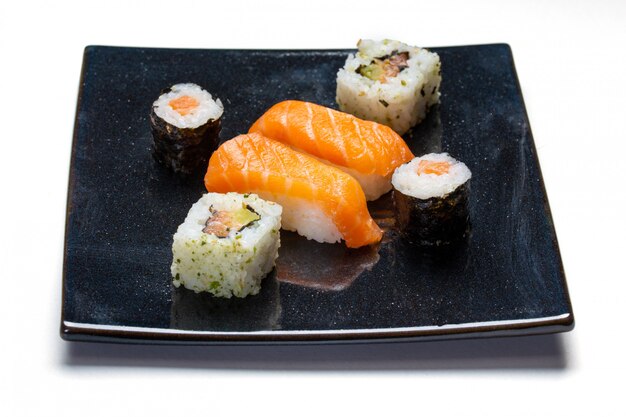 Plato negro con sushi, maki y rollos americanos