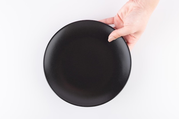 un plato negro vacío es presentado por una mano femenina