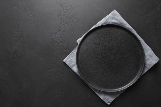 Foto plato negro vacío con toalla lila sobre fondo negro de cocina espacio para el diseño vista desde arriba