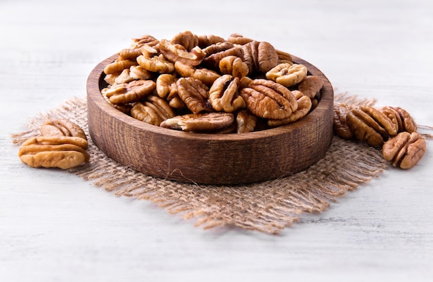 Foto plato de nueces pecanas secas sobre fondo de madera