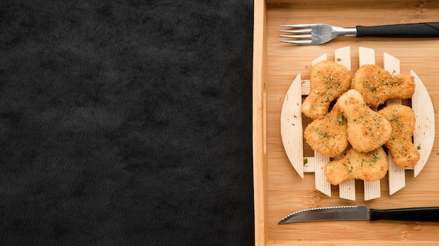 Plato con nuggets de pollo en bandeja de madera