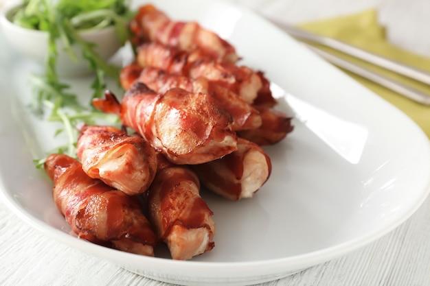 Plato con nuggets de pollo envueltos en tocino en primer plano de la mesa