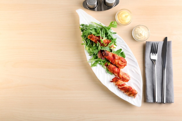 Plato con nuggets de pollo envueltos en tocino sobre la mesa