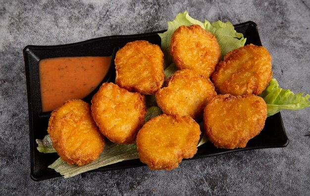 Plato de nuggets de pollo con salsa en la vista superior de la mesa rústica