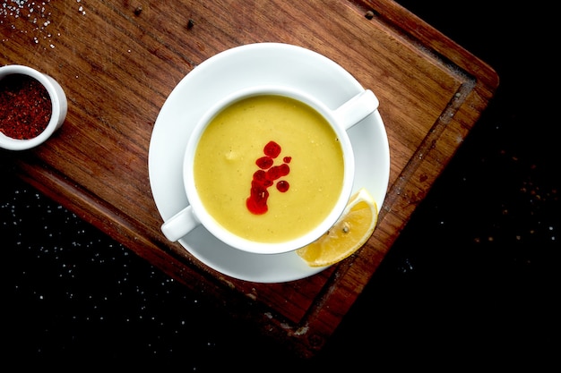 Plato oriental - una sopa de crema de lentejas amarillas en blanco sobre una mesa oscura piala