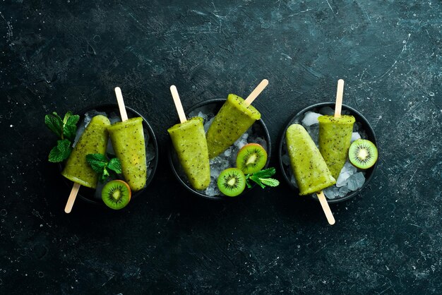 Un plato de paletas caseras con kiwi sobre un fondo de piedra negra