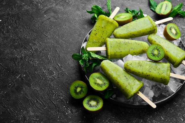 Un plato de paletas caseras con kiwi sobre un fondo de piedra negra