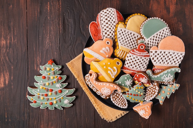 Un plato de pan de jengibre de Navidad sobre fondo marrón de madera, plano laical.