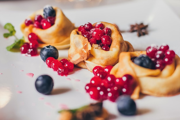 Plato de panqueques goteando caramelo con arándanos y arándanos