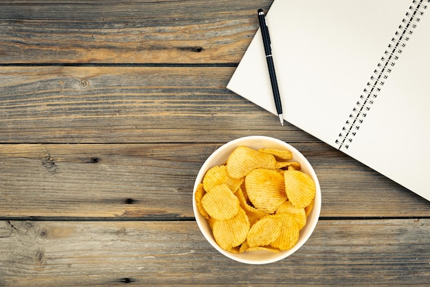 Foto un plato de papas fritas y un cuaderno en una vista superior de fondo de madera