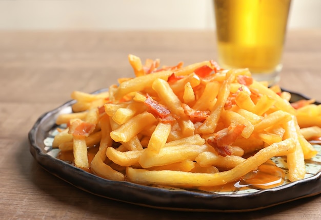 Plato con papas fritas y tocino en la mesa