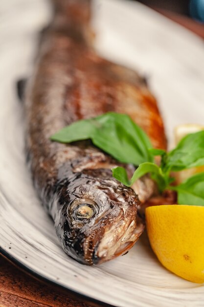 Plato de parrilla de pescado al horno entero a la parrilla en un plato con verduras y limón