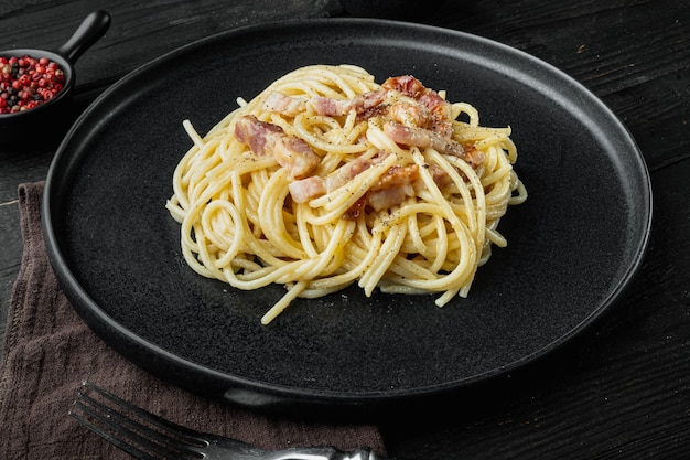 Plato de pasta carbonara. Cocina tradicional romana. Conjunto de comida italiana, sobre fondo de madera negra