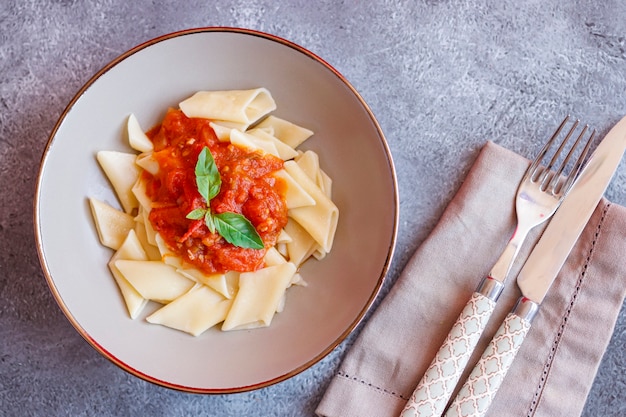 Foto plato de pasta corta con salsa de tomate y albahaca