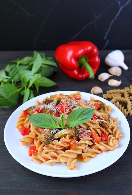 Plato de pasta fusilli integral recién cocinada en salsa de tomate en la mesa de la cocina