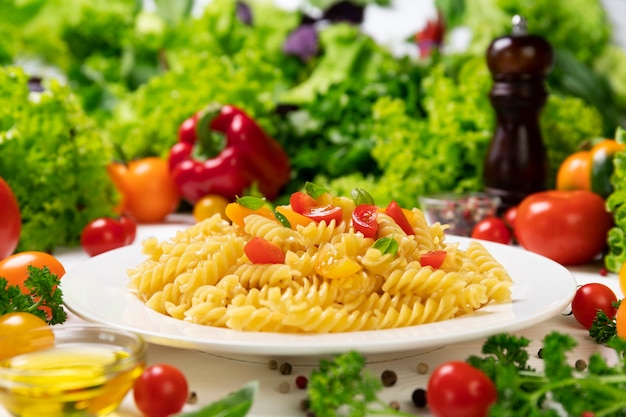 Foto plato de pasta fusilli italiana cocida con tomates y hojas de albahaca