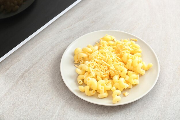 Plato con pasta y queso cerca del microondas en la mesa