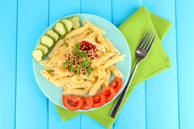 Plato de pasta Rigatoni con salsa de tomate en una mesa de madera azul