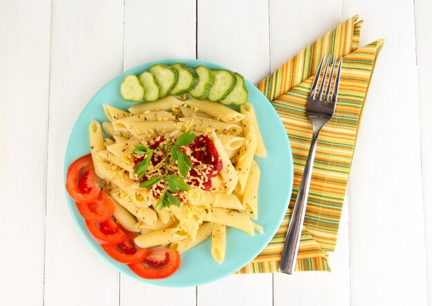 Foto plato de pasta rigatoni con salsa de tomate sobre mesa de madera blanca