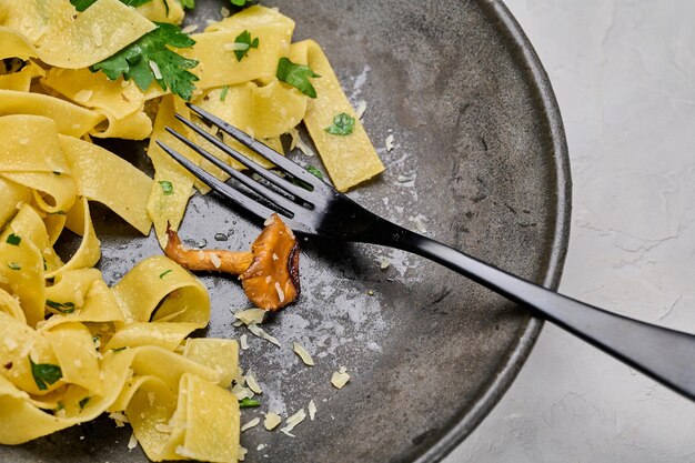 Plato de pasta tradicional pappardelle con rebozuelos comido no terminado horquilla en el