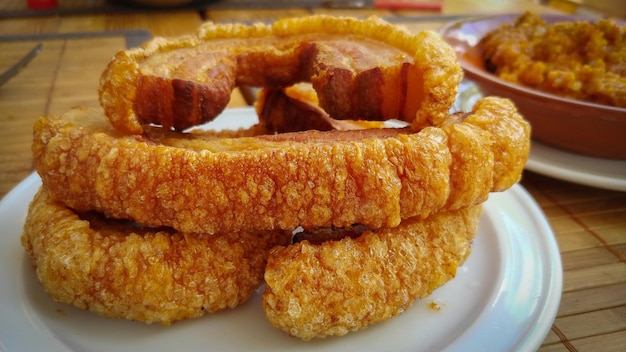 Un plato de patatas fritas de panceta de cerdo con una salsa roja al lado.