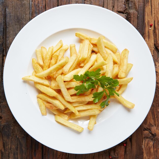 Un plato de patatas fritas con una ramita de perejil encima.