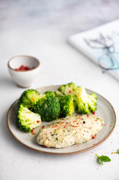 Un plato de pechuga de pollo con brócoli y pimiento rojo.