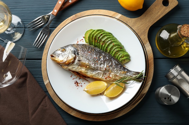 Plato con pescado dorado al horno sobre madera adornada