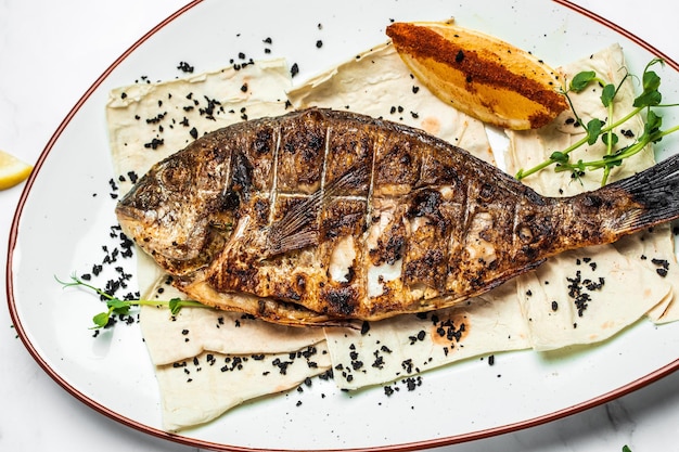 Plato con pescado dorado preparado Besugo entero a la barbacoa Parrilla de dorado al horno Almuerzo de dieta cetogénica o paleo Tendencia de comida saludable Vista superior