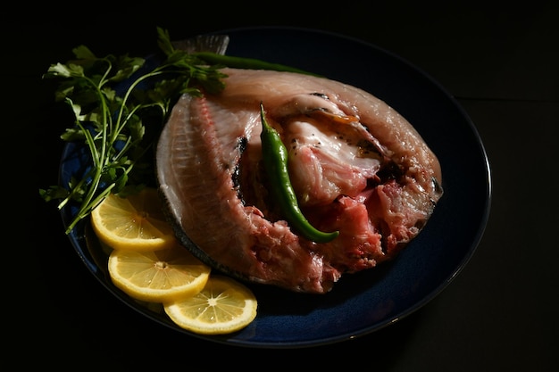 Un plato de pescado con limones y chiles verdes.