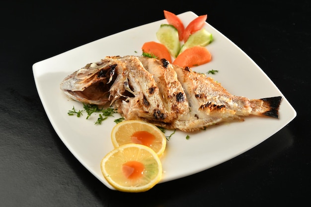 Un plato de pescado con limones y tomates