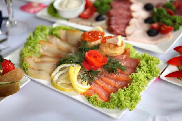 Plato de pescado con pescado salado surtido, de pie sobre la mesa de comedor decorada, junto a los demás snacks