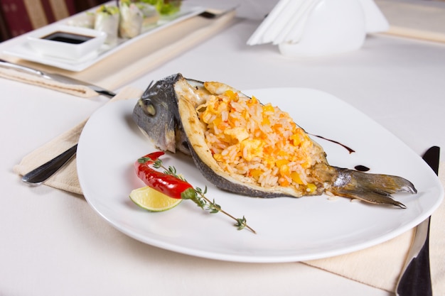 Plato de pescado relleno de arroz en la placa en el restaurante cubierto