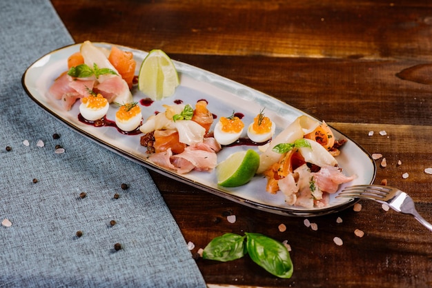 Un plato con pescado rojo, blanco, caviar y verduras en el fondo de madera