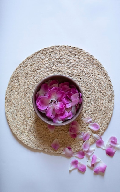 Un plato con pétalos de flores de color rosa sobre un fondo blanco.