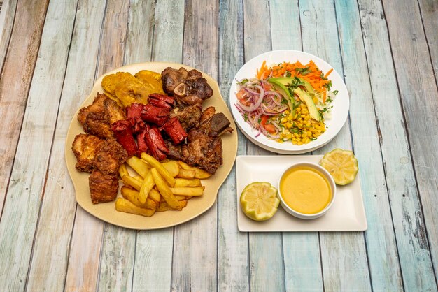 Foto un plato de picatodo cocinado en un restaurante ecuatoriano con ají amarillo papas fritas salchichas de pollo trozos de carne y plátano frito